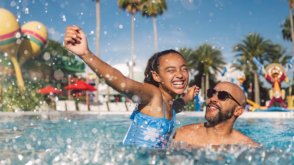 Father and daughter playing in resort pool